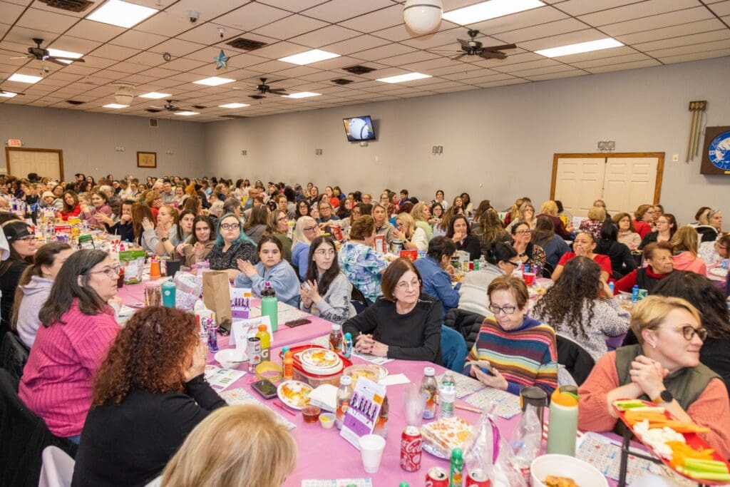 A large group gathered for a lively event in a decorated banquet hall.