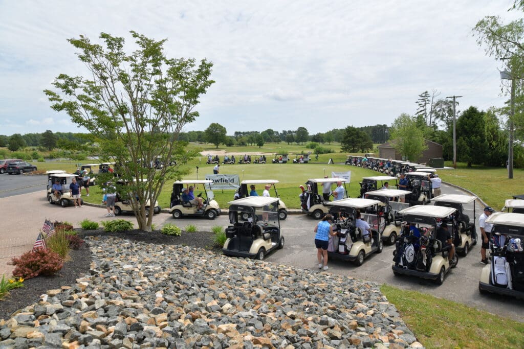 Golf carts parked near a green golf course with players preparing to start.