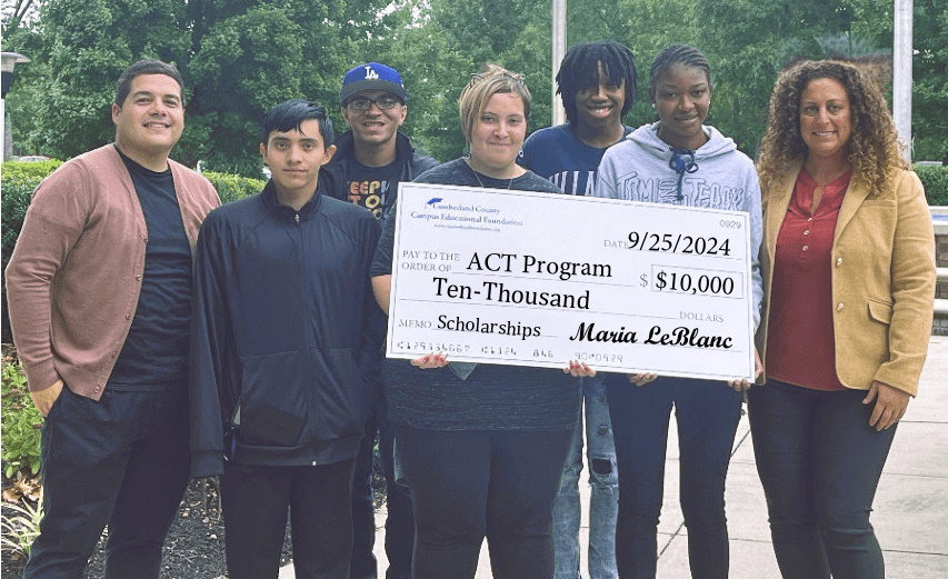 Five people holding a large $10,000 check for scholarships.