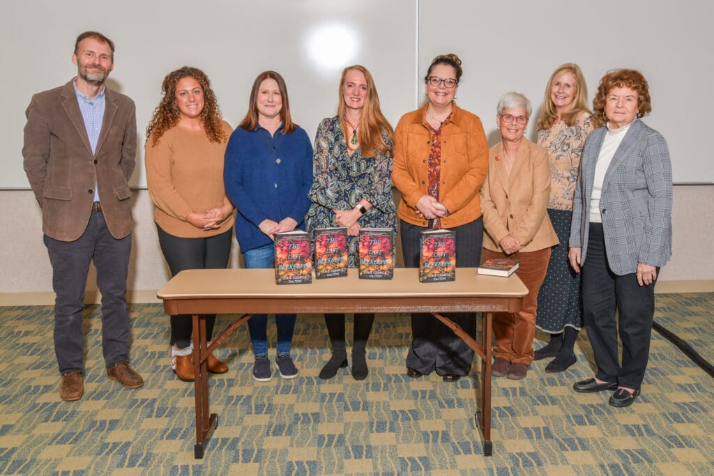 Six people standing behind a table with gift bags, smiling.