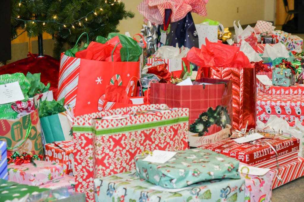 A colorful pile of wrapped Christmas presents under a tree.