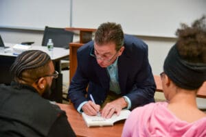 Author signing book for two students.
