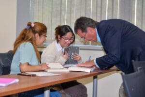 Teacher assisting two students in classroom.