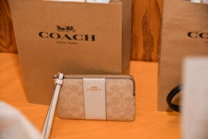 Beige Coach wristlet with shopping bag.