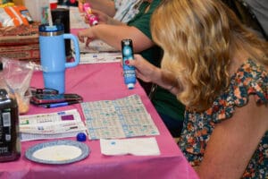 Woman playing bingo with marker and cards.