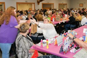 Women playing bingo at a crowded event.