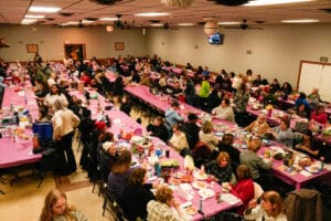Crowded community banquet with pink tablecloths