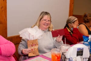 Smiling woman holding Valentine's gifts at table